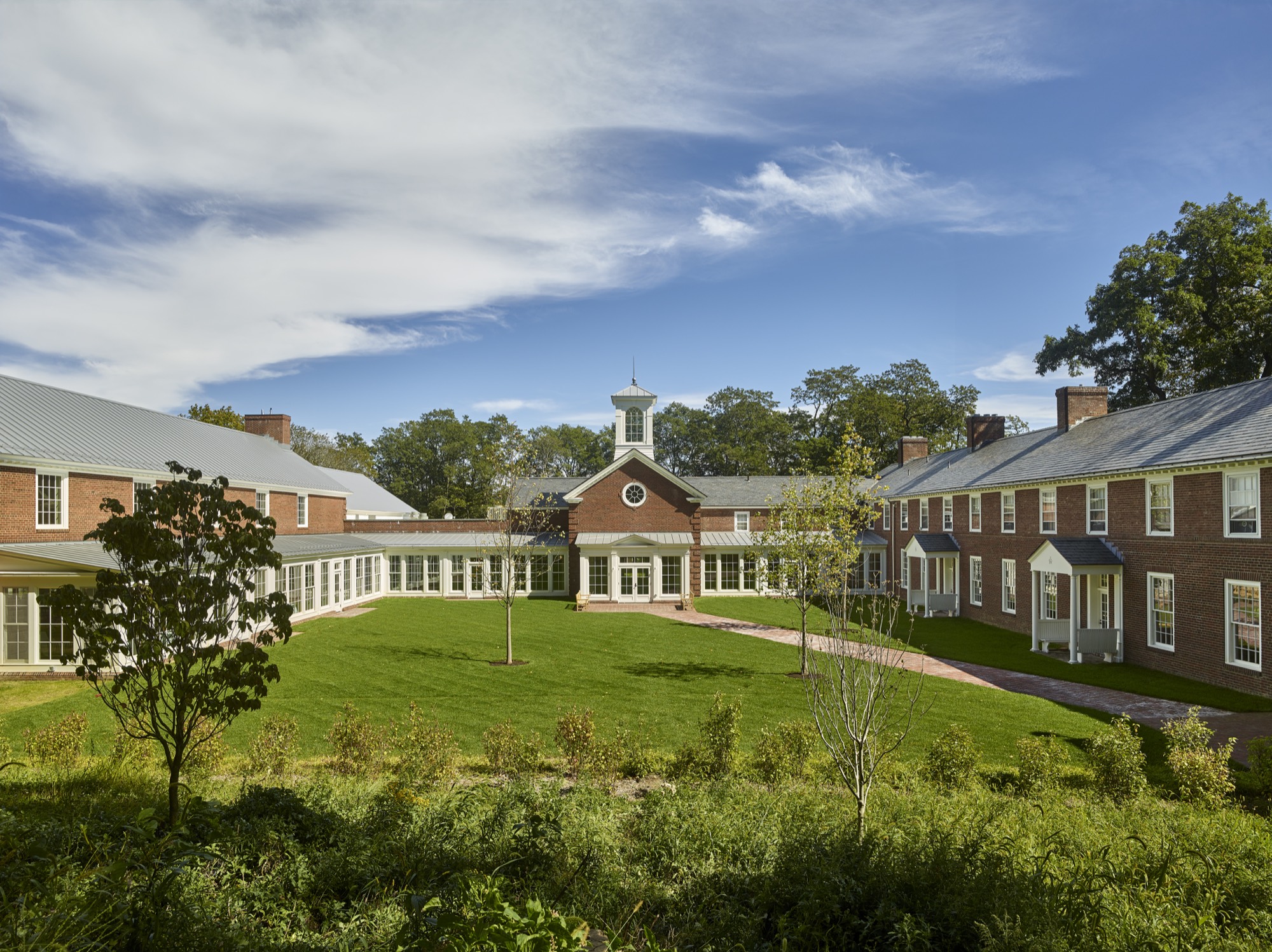 Brick campus buildings with a white cupola around a landscaped quadrangle